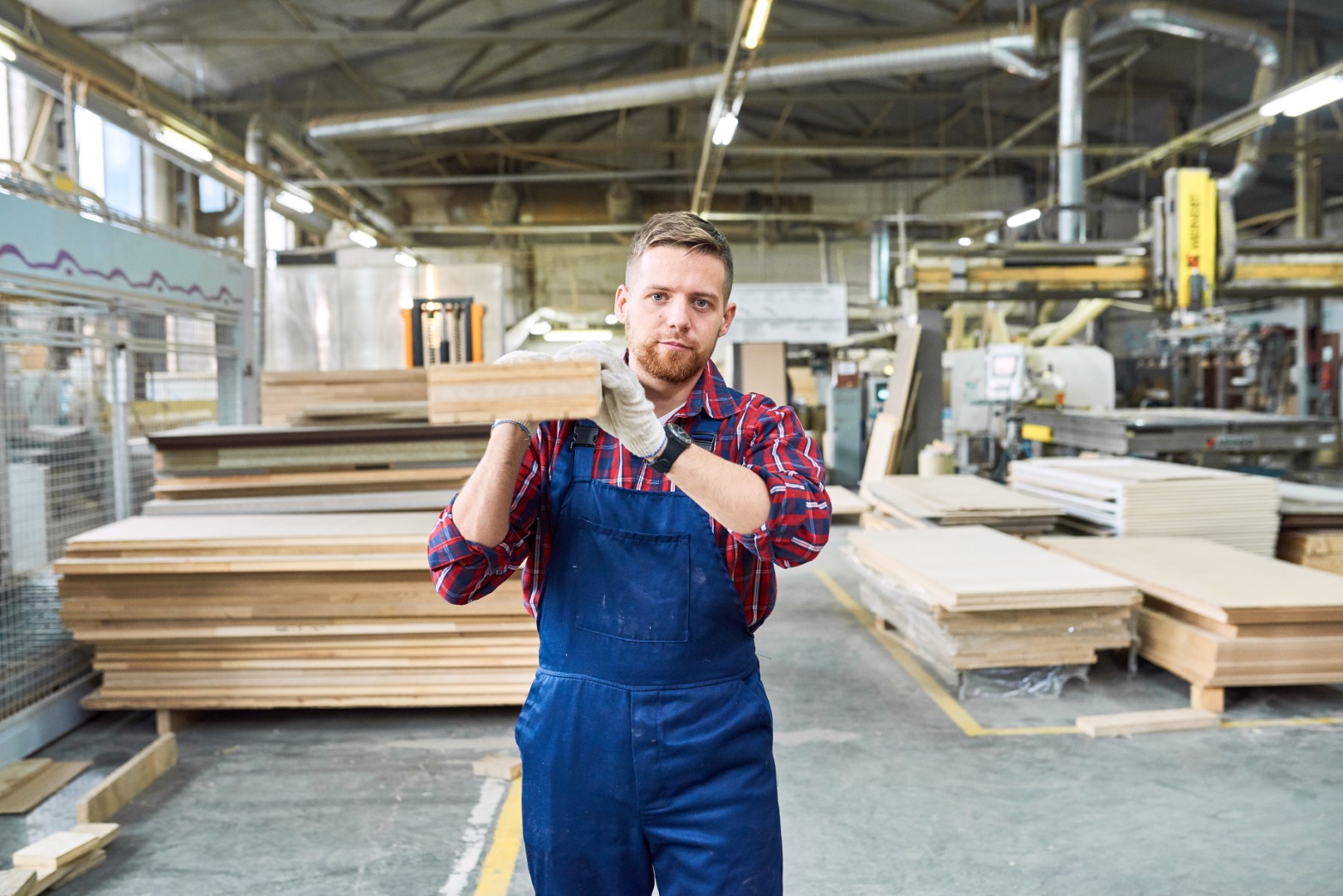 Young Man Carrying Wooden Board at Factory